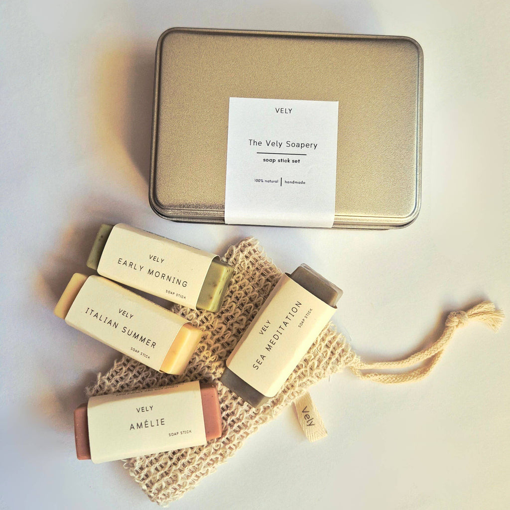 Set of 4 VELY soap bars with a mesh bag and tin container on a light background